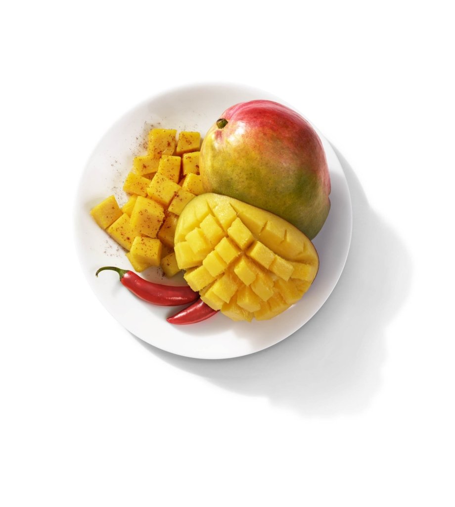 Spicy mangoes and peppers on white background