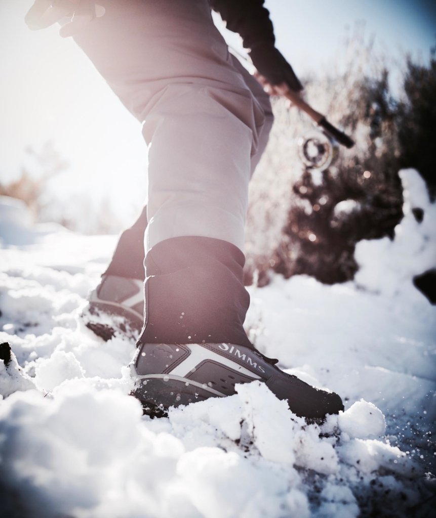 Fly fisherman's shoes trekking up a snowy hill